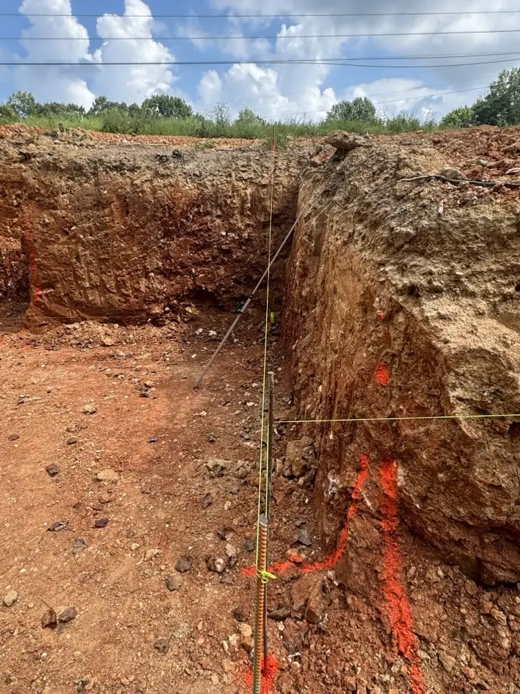 Corner of a basement dig in red clay with a string line set for grade
