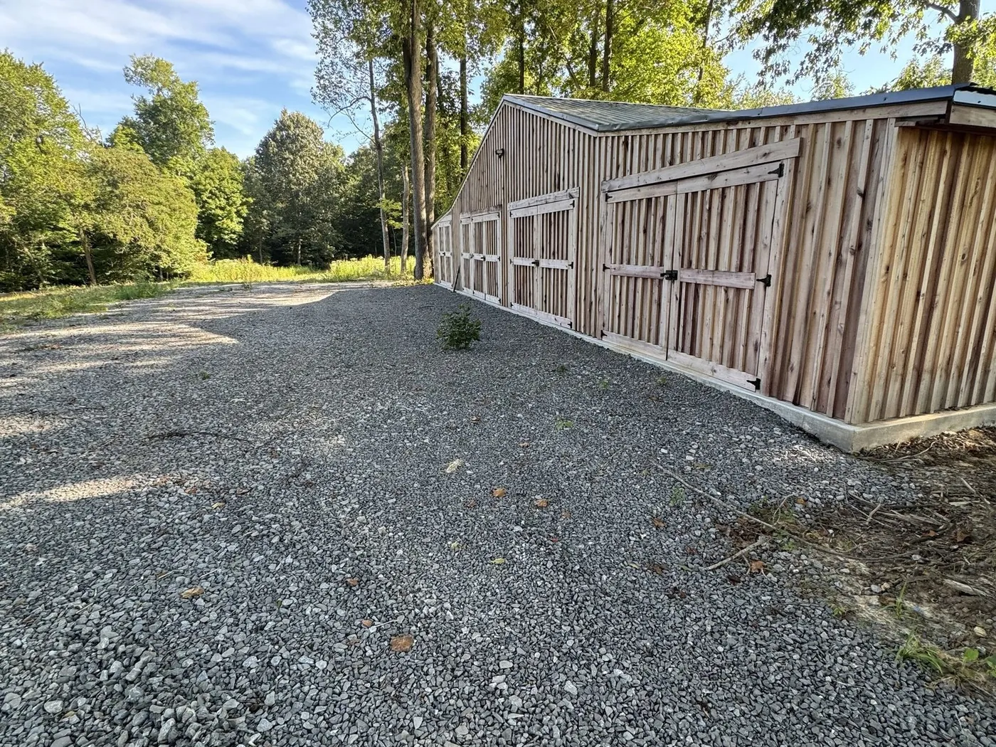 Gravel drive laid along a board and batten barn
